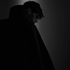 a man in a dark room wearing a hooded jacket