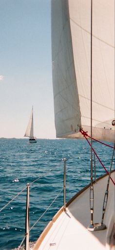 a sailboat sailing in the ocean with another boat on the water behind it,