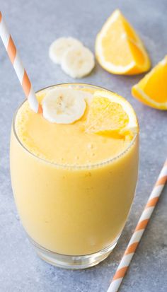 a smoothie with banana slices and oranges on the side is ready to be eaten