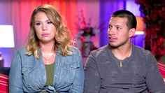 a man and woman sitting next to each other in front of a tv screen with the words umm on it