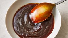 a white bowl filled with chocolate sauce and a wooden spoon in the bowl next to it