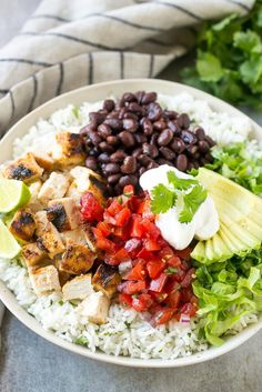 a bowl filled with rice, beans, avocado, and chicken on top of it