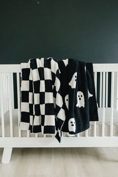 two black and white blankets are hanging on a crib