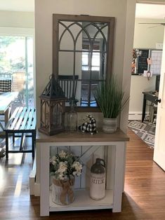 a shelf with some plants and vases on top of it in a living room