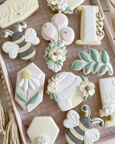 decorated cookies in the shape of flowers and bees on a tray with twine strings