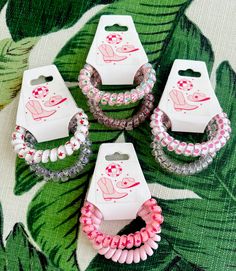 four bracelets with pink and white designs on them sitting on top of a table