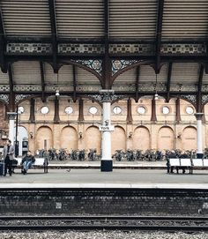 a train station with people sitting on benches and bikes parked in the backgroud