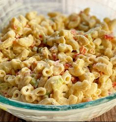 a bowl filled with macaroni salad on top of a wooden table