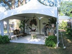 a white tent with chairs and potted plants