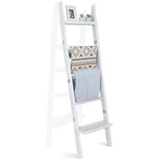 a white ladder shelf with a blanket on it