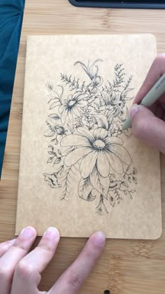 a person is drawing flowers on a piece of paper