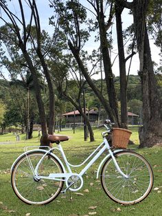 a white bicycle parked in the grass next to trees