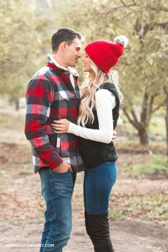 a man and woman standing next to each other in the woods