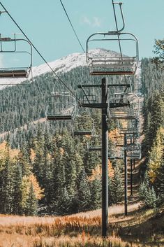 a ski lift going up the side of a mountain with trees in the foreground