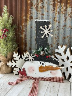 a snowman made out of wood sitting on top of a wooden table next to christmas decorations