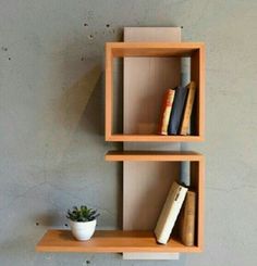 two wooden shelves with books and a plant on one shelf, against a gray wall