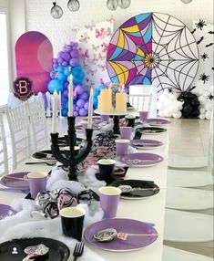 the table is set with purple and white plates, black candles, and spider web decorations