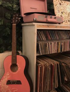 an old pink guitar sitting next to a record player