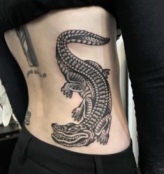 a black and white photo of a woman's stomach with an alligator tattoo on it