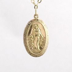 14k gold fill Virgin Mary pendant hangs from a 14k gold fill chain. Pendant is approximately 3/4 of an inch in length. The third image shows the detail on the back of the pendant. Also comes in sterling silver. I also have a smaller version of the pendant available in my shop. LENGTH - Necklace on the model is 16 inches long (the model's neck circumference is 12 inches). YOUR ORDER - Choose either gold fill or sterling silver in the drop-down menu. - Select the length in the drop-down menu. If y Gold Round Pendant With Miraculous Medal, Gold Miraculous Medal Round Pendant Jewelry, Gold Nickel-free Necklace For Memorial, Gold Jewelry With Charms For Commemoration, Commemorative Gold Charm Jewelry, Commemorative Gold Jewelry With Charms, Nickel-free Gold Necklace With Oval Pendant, Nickel Free Gold Oval Pendant Necklace, Nickel-free Gold Oval Pendant Necklace