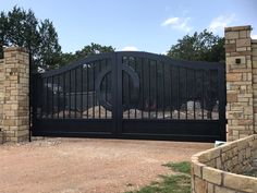 a black gate with a circular design in the middle and two brick pillars on either side