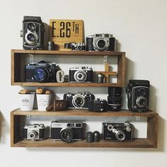 three wooden shelves with cameras on them