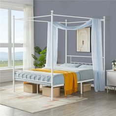 a white bed sitting in a bedroom next to a dresser and window on top of a hard wood floor