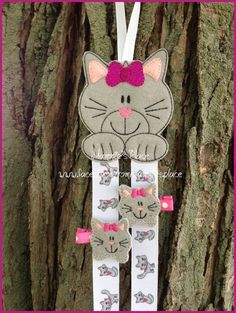 a cat ornament hanging from a tree with pink bows on it's head