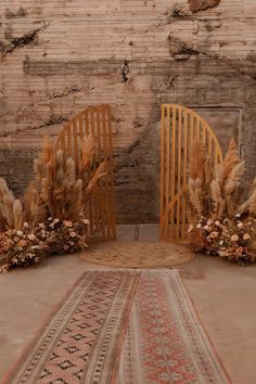 two wooden chairs sitting next to each other on top of a rug in front of a brick wall