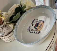 a blue and white bowl sitting on top of a table next to a vase with flowers