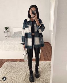 a woman taking a selfie while standing in front of a bed and holding a camera