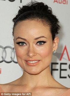 a close up of a person with blue eyes and an orange dress on the red carpet