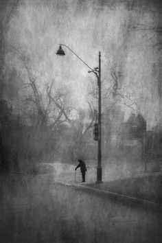 a person is walking down the street with an umbrella on a foggy day in black and white