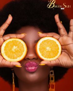 a woman holding two halves of an orange in front of her eyes