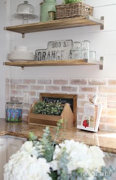 the shelves above the kitchen counter are filled with dishes and flowers on top of them