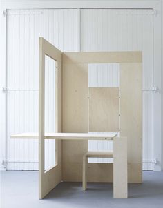 an empty room with a table and bench in the corner, all made out of plywood