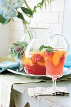 two glasses filled with watermelon and orange juice sitting on a table next to a pitcher