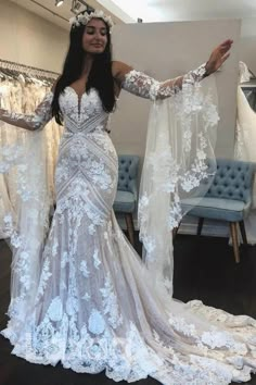 a woman is standing in front of wedding dresses and holding her arms out to the side