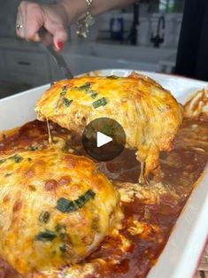 a person is cutting into some food in a white casserole dish with cheese and spinach on top