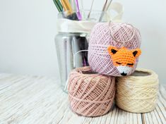 two balls of yarn are sitting next to each other on a table with pens and pencils