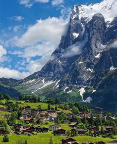 the mountains are covered in snow and green grass, with houses on either side of them