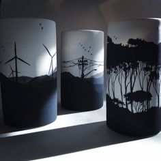 three black and white vases sitting on top of a table