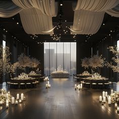 a room filled with lots of tables covered in white flowers and lit candles next to tall windows