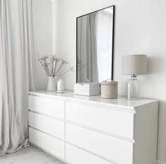 a white dresser with a mirror, vases and lamp on it in a room