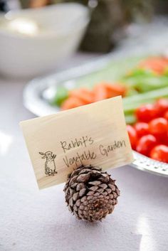 a pine cone sitting on top of a table next to some veggies and a sign