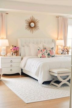 a white bed sitting in a bedroom on top of a hard wood floor next to two lamps