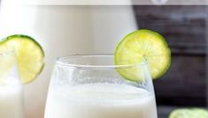 two glasses filled with milk and lime slices