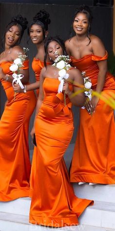 four women in orange dresses posing for the camera