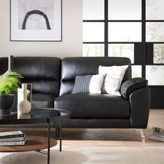 a living room with black leather furniture and pictures on the wall