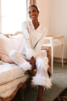 Introducing the Bianca Pajamas in White - a luxurious and stylish choice for your bridal party! Made from soft white satin, these pajamas feature a functional button-down top with a bust pocket and delicate feather detailing on the sleeves. The matching wide-leg pants with feather detailing at the ankle and elastic waistband ensure comfort and ease of movement, perfect for lounging or getting ready on your special day. Make memories with your bridal party that you won't forget with the Bianca Pa White Silk Pajamas Aesthetic, Satin Pjs Bridesmaids, White Bridal Pajama Set, Bridesmaid Pajamas Winter, White Bride Pajamas, Bridal Shower Pajamas, White Silk Pjs, Wedding Pjs Bride, Winter Wedding Pajamas